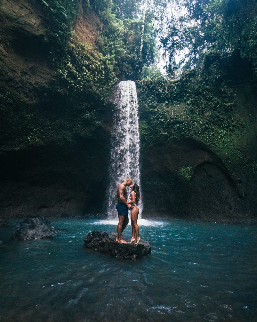 couple kissing before a waterfall